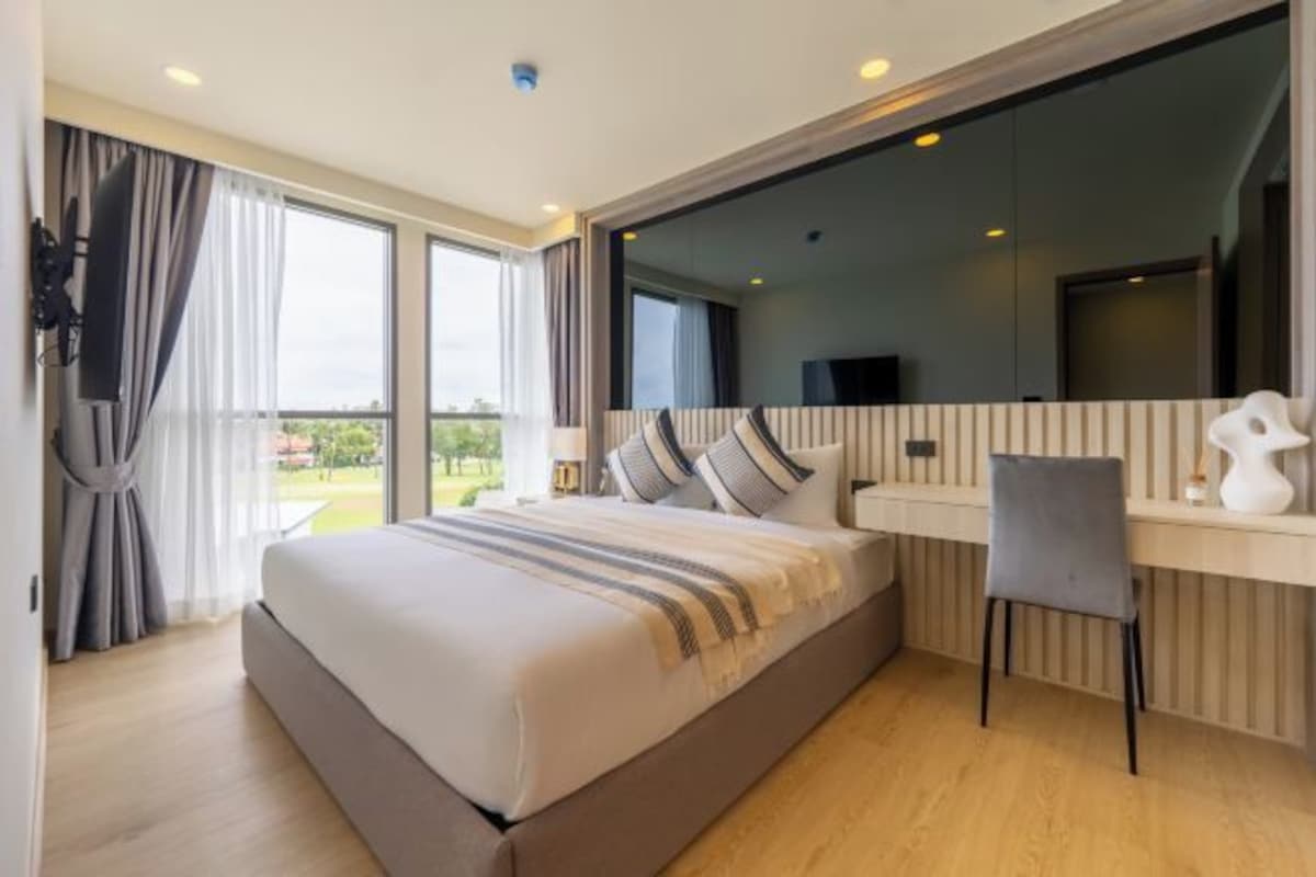 A modern hotel room with a large bed, a desk, and a TV.