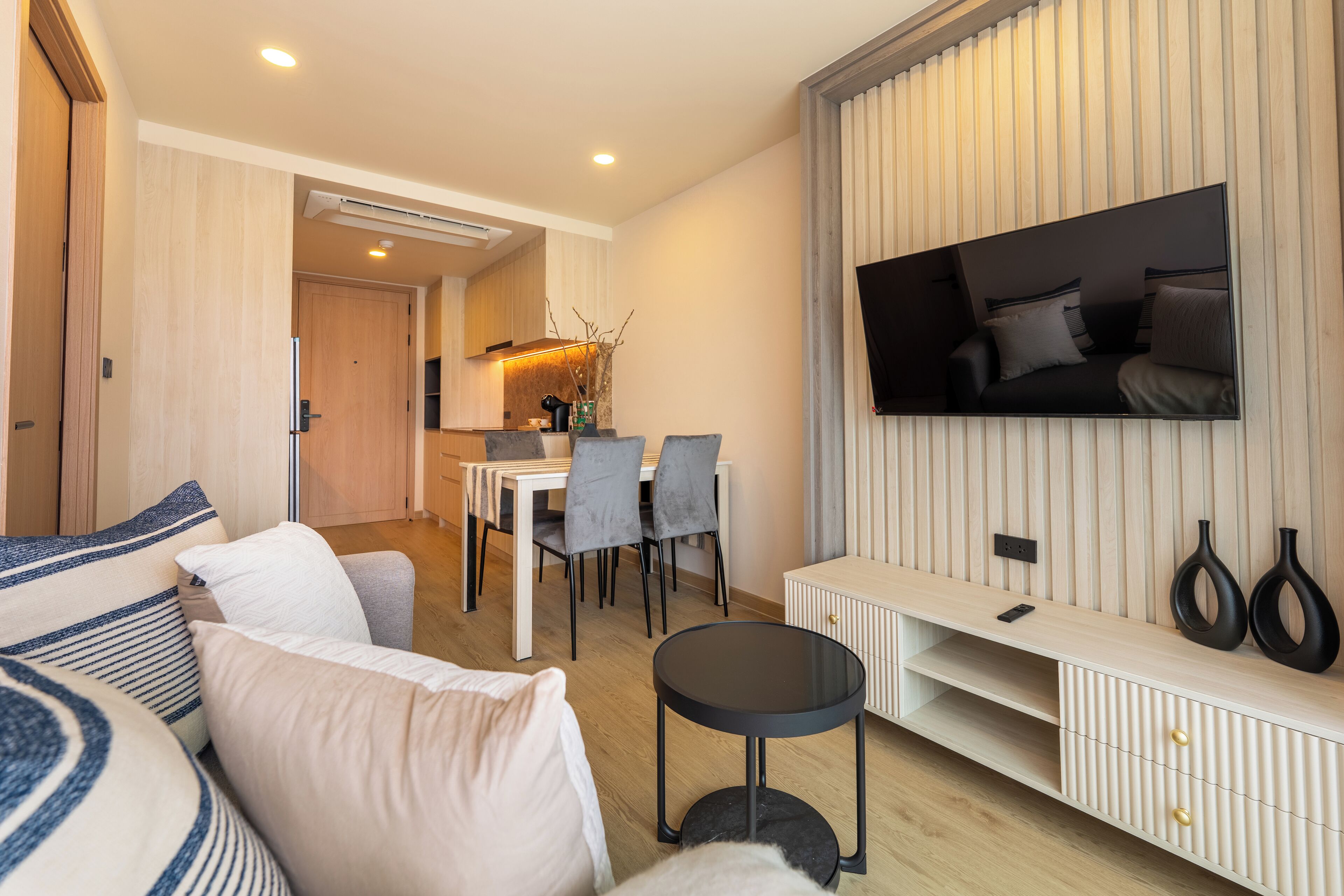 Un salon moderne comprenant un canapé, un téléviseur et un coin repas avec des chaises et une table.