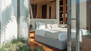A modern bedroom with a large bed, a glass door leading to a balcony, and a wooden wardrobe. - The Ozone Residences Bangtao (Choeng Thale)