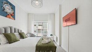 A modern hotel room with a large bed, a view of the city, and a framed sign on the wall. - GuestReady - An elegant stay in the city centre (Porto)
