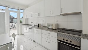 A modern kitchen with white cabinets, a built-in oven, and a microwave. - GuestReady - An elegant stay in the city centre (Porto)