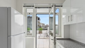 A modern kitchen with a sliding glass door leading to a balcony with outdoor furniture. - GuestReady - An elegant stay in the city centre (Porto)
