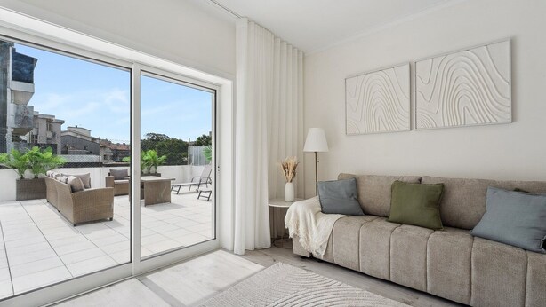 A modern living room with a sliding glass door leading to a balcony, a sofa with cushions, a lamp, and wall art. - GuestReady - An elegant stay in the city centre (Porto)