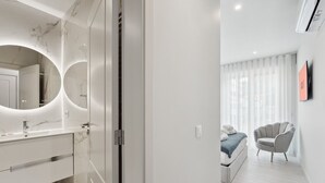 A modern bathroom with a marble vanity, a large mirror, and a glass shower enclosure.