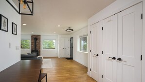 A spacious room with a wooden dining table, white doors, and a brick fireplace.