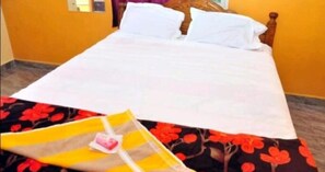 Cama com lençóis brancos num quarto com paredes amarelas.