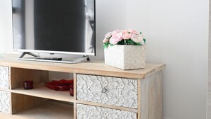 A flat-screen TV on a wooden console with decorative drawers and a white vase with pink flowers. - P068 - Porto Recanati, new two-room apartment with panoramic terrace (Porto Recanati)
