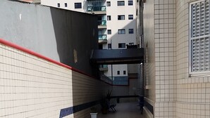 A narrow corridor with tiled walls and floor, leading to a building entrance. - Large apartment, sea view with Wi-Fi (Guilhermina Praia Grande)