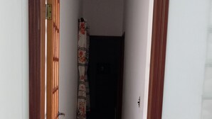 A narrow hallway with a wooden door frame, a tiled floor, and a curtain with a floral pattern. - Large apartment, sea view with Wi-Fi (Guilhermina Praia Grande)