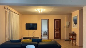 A living room with a sectional sofa, a flat-screen TV, a dining table, and a ceiling light fixture. - Villa la colle sur loup close to the sea, ideal family, near village (La Colle-sur-Loup)