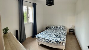 A bedroom with a bed, a window with curtains, a bedside lamp, a small table, and a potted plant. - Villa la colle sur loup close to the sea, ideal family, near village (La Colle-sur-Loup)