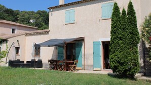 A two-story house with a patio area featuring a table and chairs. - Villa la colle sur loup close to the sea, ideal family, near village (La Colle-sur-Loup)