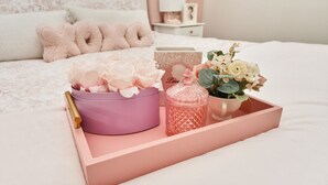A neatly arranged bedroom with a bed, pillows, a bedside table, and a tray with decorative items.