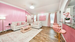 A pink-themed living room with a white sofa, a coffee table, and pink chairs.