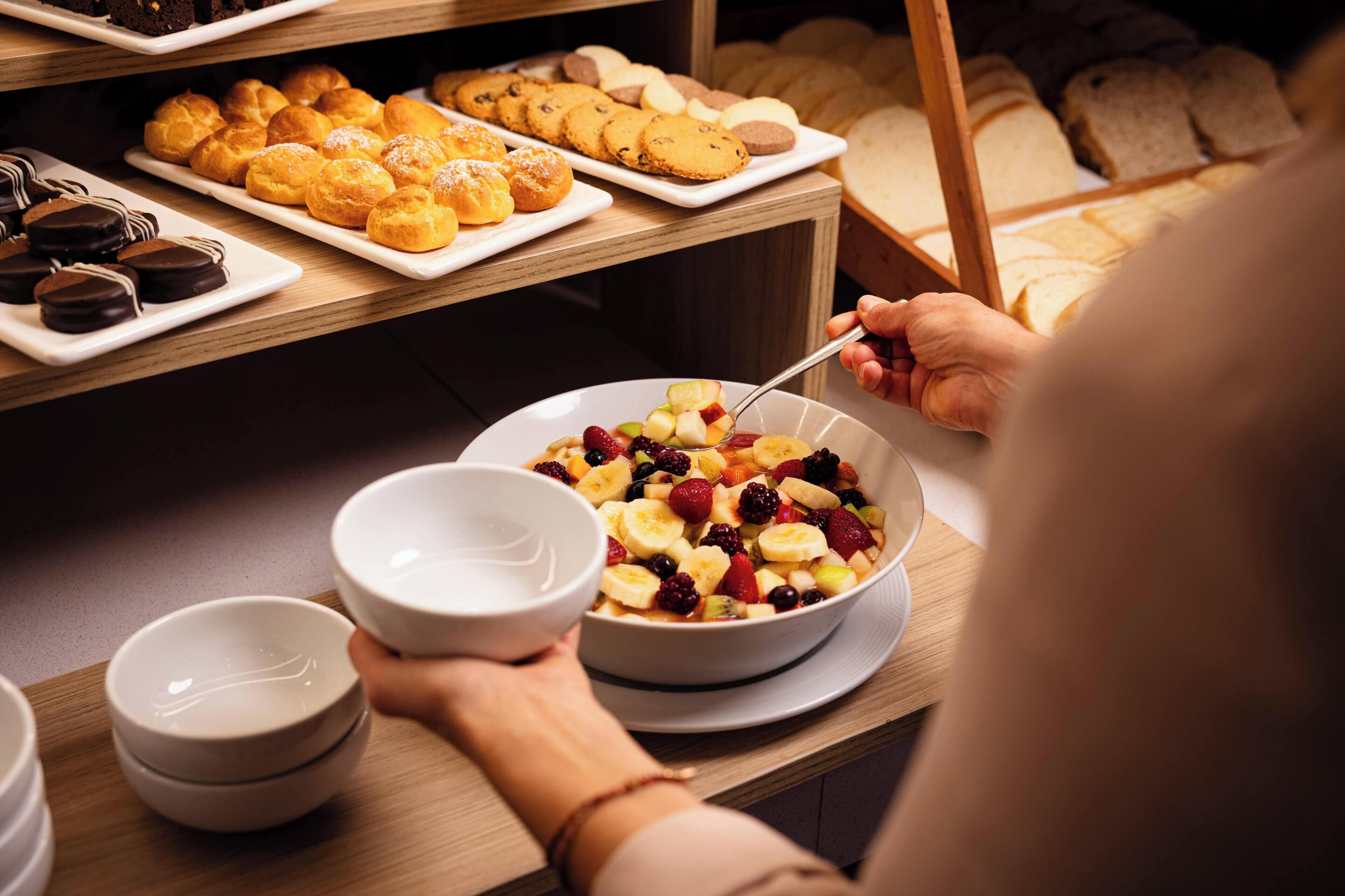 A buffet with various baked goods and a bowl of fruit salad.