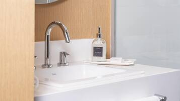Un baño moderno con un lavamanos blanco, un grifo cromado y un dispensador de jabón.