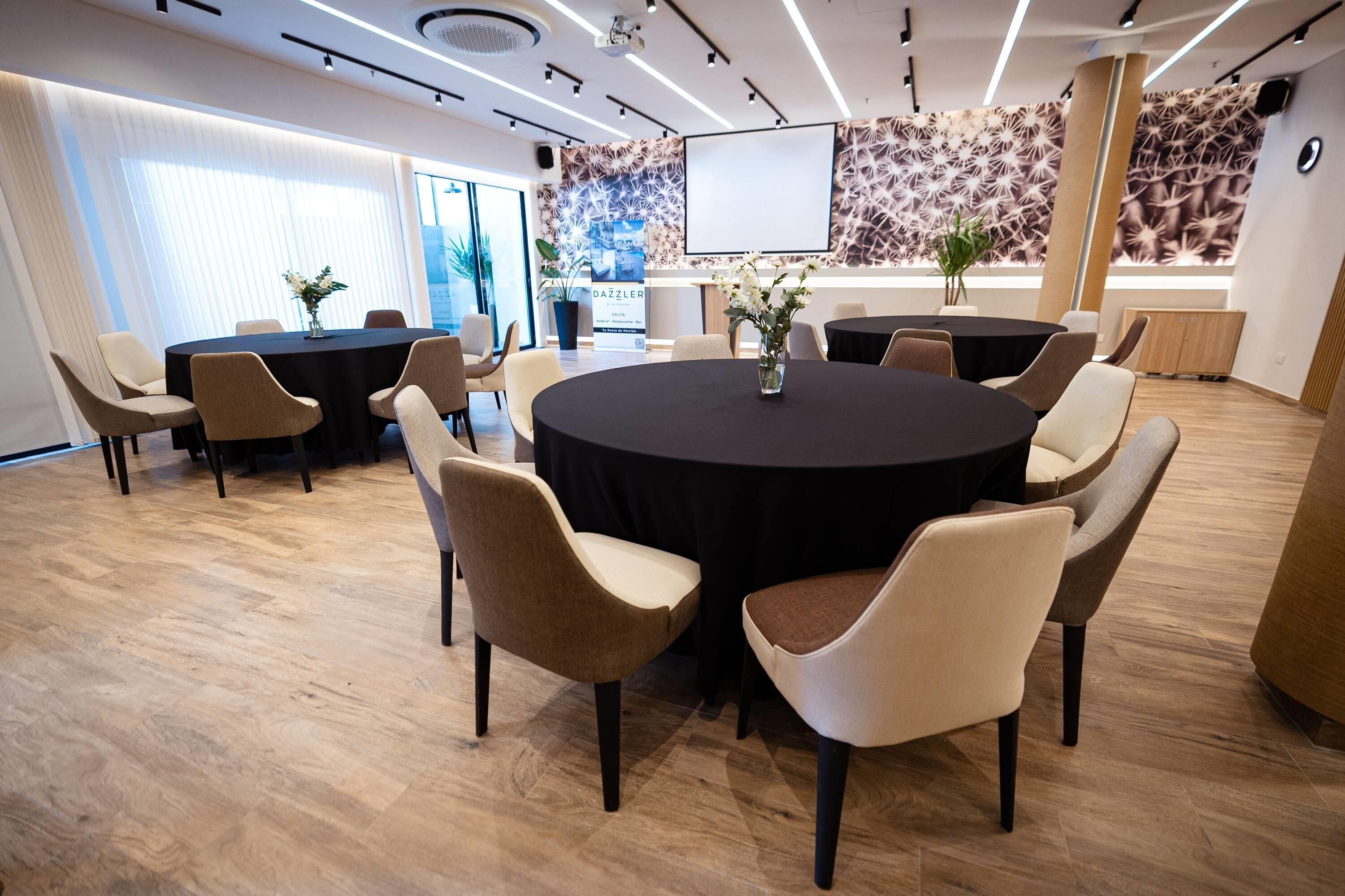 A conference room with a round table, chairs, and a projector screen.