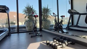 A gym with exercise equipment, large windows, and a view of the outside.