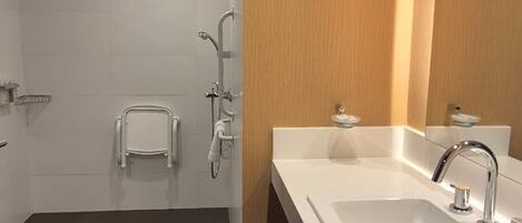 Un baño moderno con ducha, lavamanos y espejo.