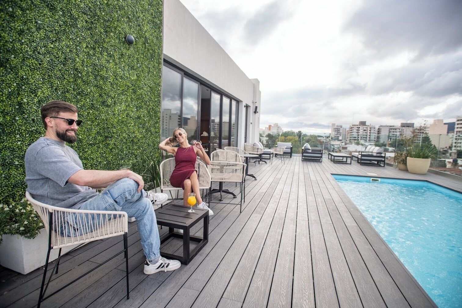 Une piscine sur le toit, avec une terrasse en bois, des sièges et une vue sur le panorama urbain.