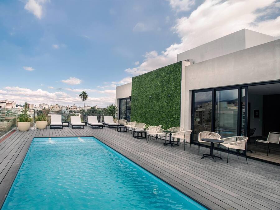 Una piscina al aire libre, sombrillas, sillones reclinables de piscina