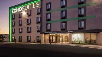 Un hotel llamado 'Echosuites' con un diseño moderno, que presenta un llamativo letrero de neón, ventanas amplias y una entrada visible.