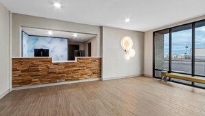 Un espace d’accueil moderne, avec un comptoir de réception en bois, une grande fenêtre donnant sur la rue et un banc placé près de la fenêtre.