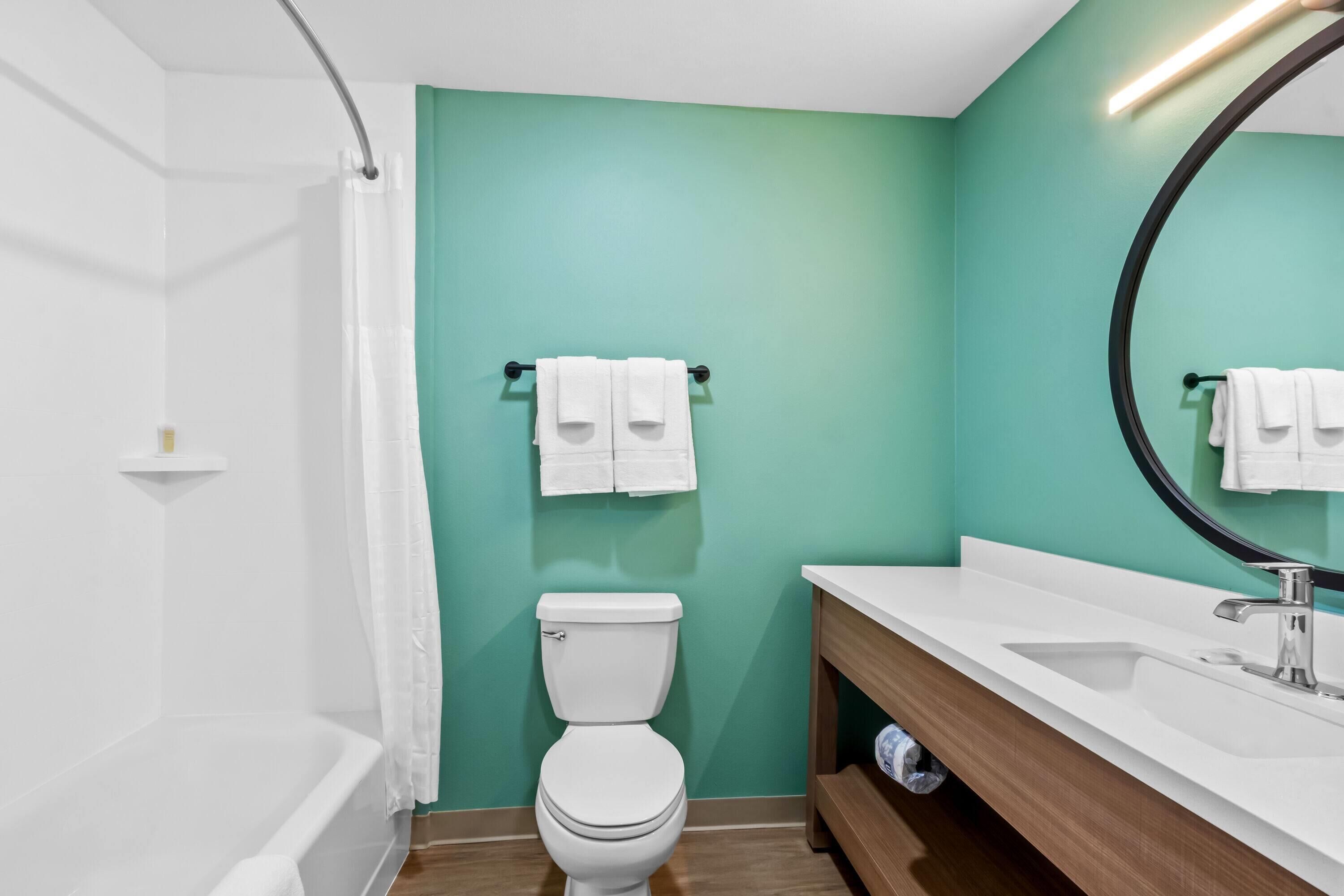 A modern bathroom with a white toilet, a white sink, and a large mirror.