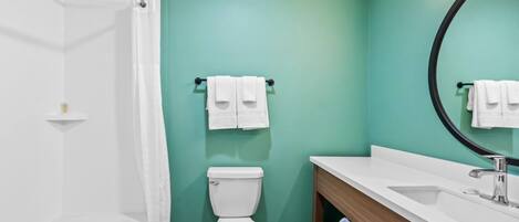 A modern bathroom with a white toilet, a white sink, and a large mirror.