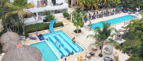Un complexe hôtelier doté de plusieurs piscines, d’espaces de détente et de bâtiments à toits de chaume.