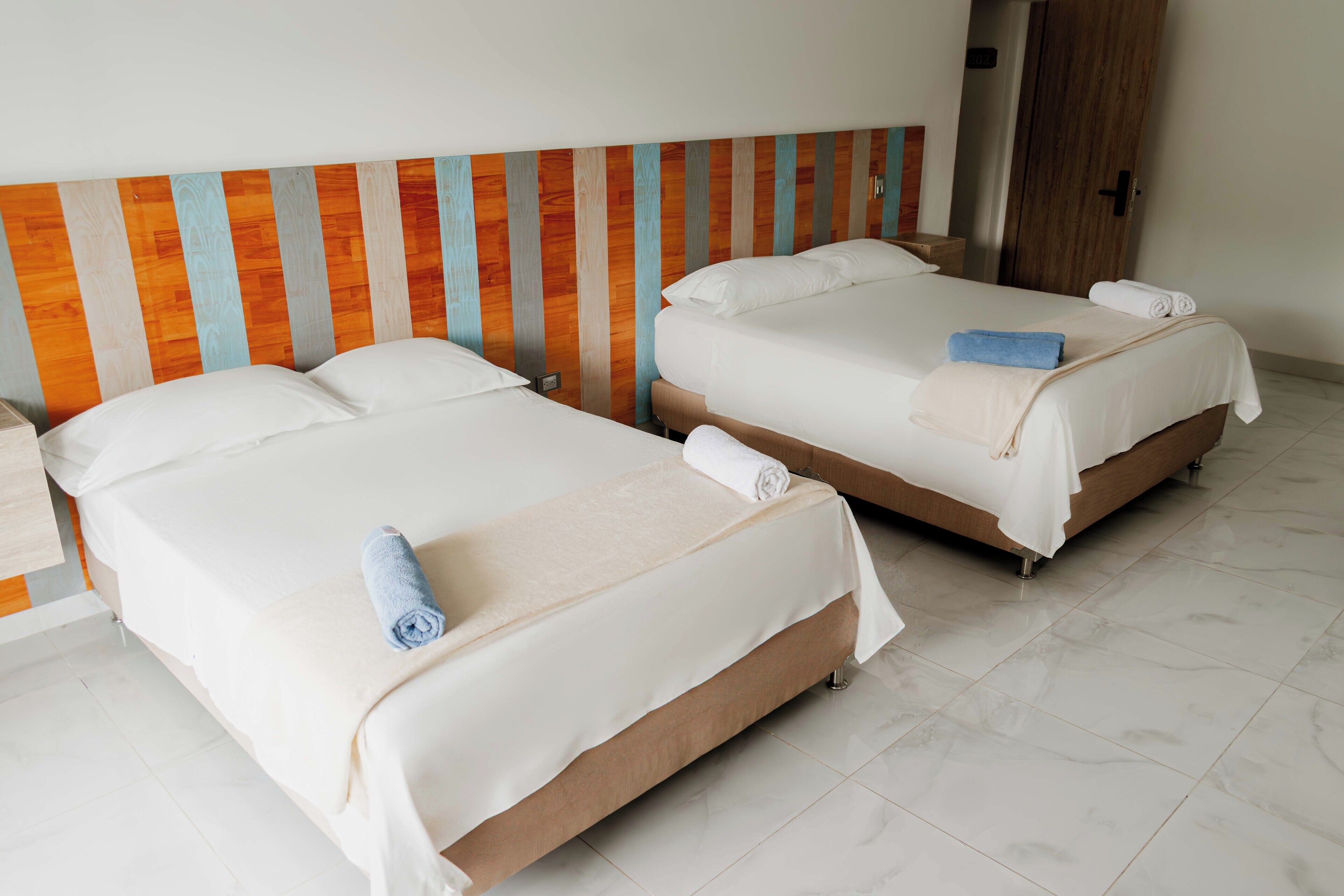 Two single beds with wooden headboards, white linens, and towels.