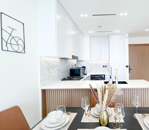Une cuisine moderne avec des meubles blancs, un îlot central et un coin repas aménagé pour prendre un repas.
