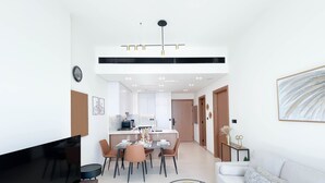 Ein modernes Wohnzimmer mit Flachbildfernseher, einer Couch und einem Essbereich mit Tisch und Stühlen.