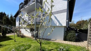 A two-story building with a balcony, a small tree in the yard, and a clear sky. - Apartment 'Meisteroffice Im Sackgässle' with Shared Garden and Wi-Fi (Dornstadt)