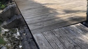 A wooden deck with a stone wall and a window. - Apartment 'Meisteroffice Im Sackgässle' with Shared Garden and Wi-Fi (Dornstadt)
