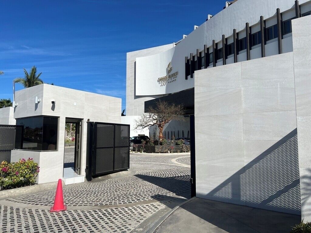 A modern building with a large entrance, a gated driveway, and a clear sky.