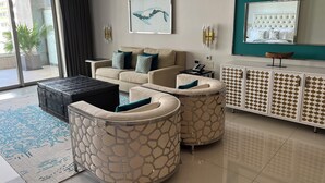 A modern living room with a sofa, two armchairs, a coffee table, a cabinet, and a large window. - Cabo San Lucas! - It's your choice - Jr. Suite, 1 or 2-bedroom resort stay! (Cabo San Lucas)