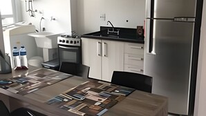 Ett modernt kök med ett kylskåp i rostfritt stål, en inbyggd ugn och en mikrovågsugn. Här finns ett matbord med stolar och en dekorativ bordslöpare.