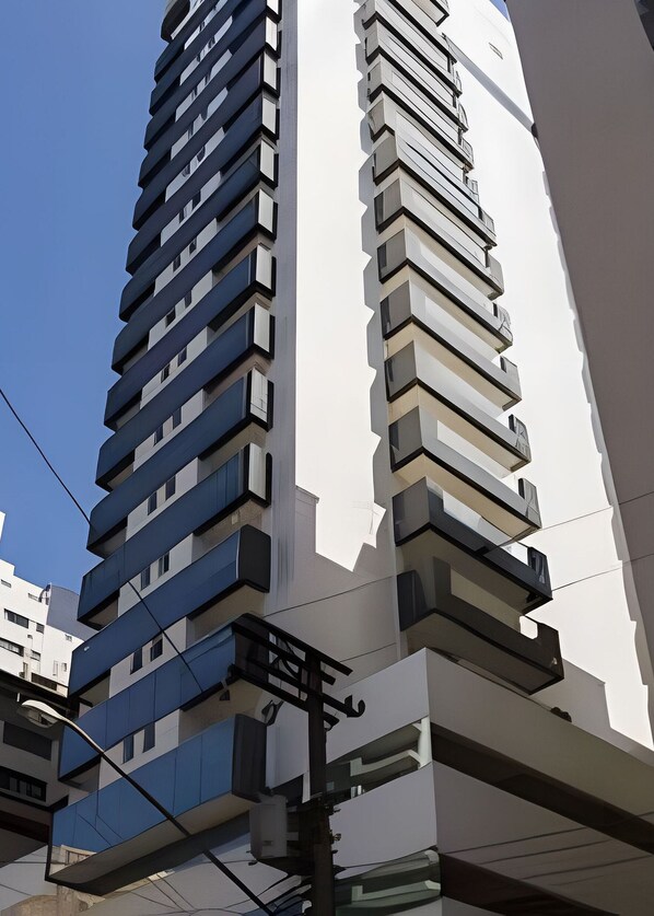 A tall, modern building with multiple balconies and a clear sky. - Latitude (Santos)