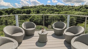 A deck with wicker chairs and a small table, overlooking a lush green landscape. - 1 Bryn Beudy (Narberth)