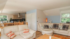 A spacious living area with two sofas, a coffee table, and a kitchen in the background. - 1 Bryn Beudy (Narberth)