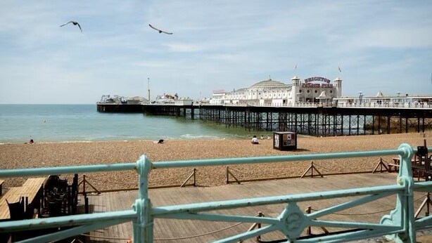 Una playa con un muelle y un edificio que dice 'Brighton Pier'.