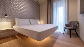 A modern bedroom with a large bed, a chair, and a patterned wall.