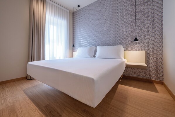 A modern hotel room with a large bed, a patterned wall, and a window with curtains. - Oriana Homèl Milano (Milan)