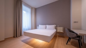 A modern hotel room with a large bed, a desk, and a patterned wall. - Oriana Homèl Milano (Milan)