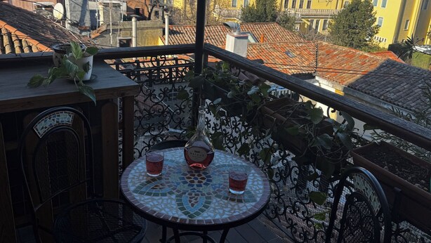 A balcony with a round table, two chairs, a bottle, and two glasses. - Charming 2-bedroom apartment with AC, WiFi in awesome Venice (Venice)