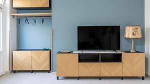 A modern living room with a TV on a wooden cabinet, a lamp, and a blue wall. - Casa Mimmo With Garden by Wonderful Italy (Syracuse)