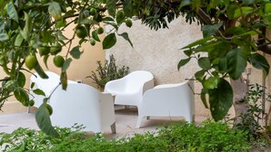 A patio area with white chairs and a beige wall. - Casa Mimmo With Garden by Wonderful Italy (Syracuse)