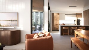 Een moderne woonkamer met een bank, een houten eettafel en een keukenhoek met houten kasten en een groot raam.