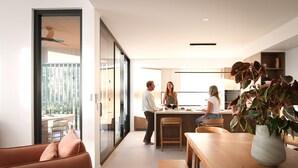 Een moderne keuken met een eethoek, een schuifpui naar een balkon, en een plant in een pot op de tafel.